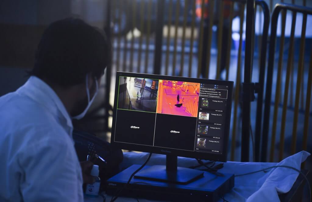 A railway employee monitors thermal images on a screen as passengers arrive to board a train to Rawalpindi at a station after the government eased a lockdown imposed to prevent the spread of the COVID-19 coronavirus in Lahore 
