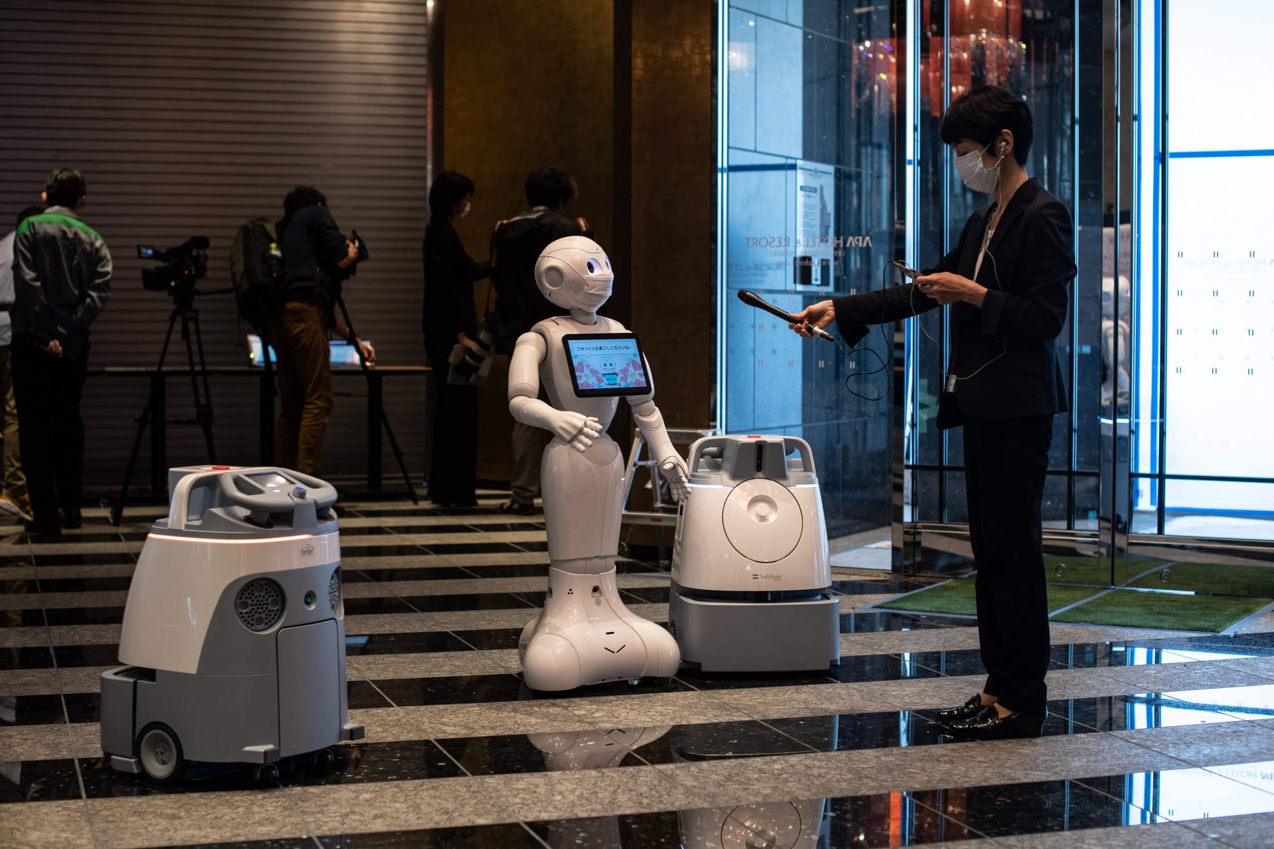 Pepper with two other cleaning robots in the lobby of a hotel